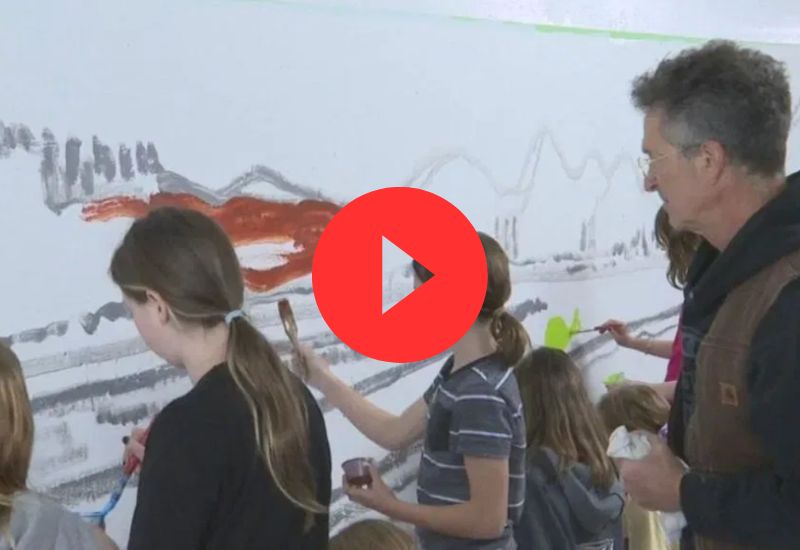 Paul Blumenthal painting a mural with school children.